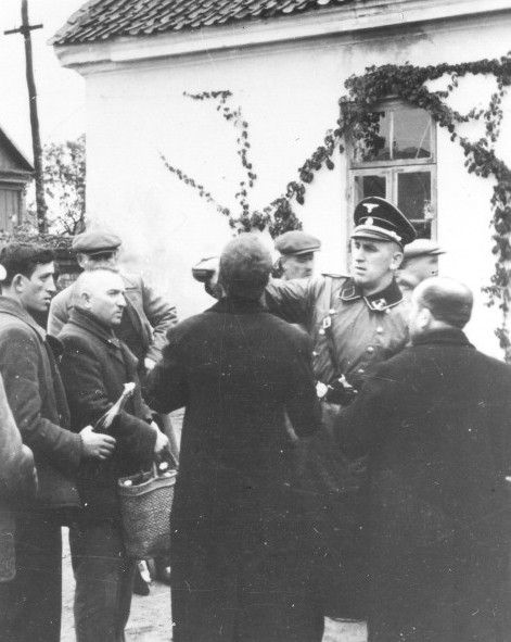 An SS officer in Raciaz forcing a Jew to drink from a bottle.